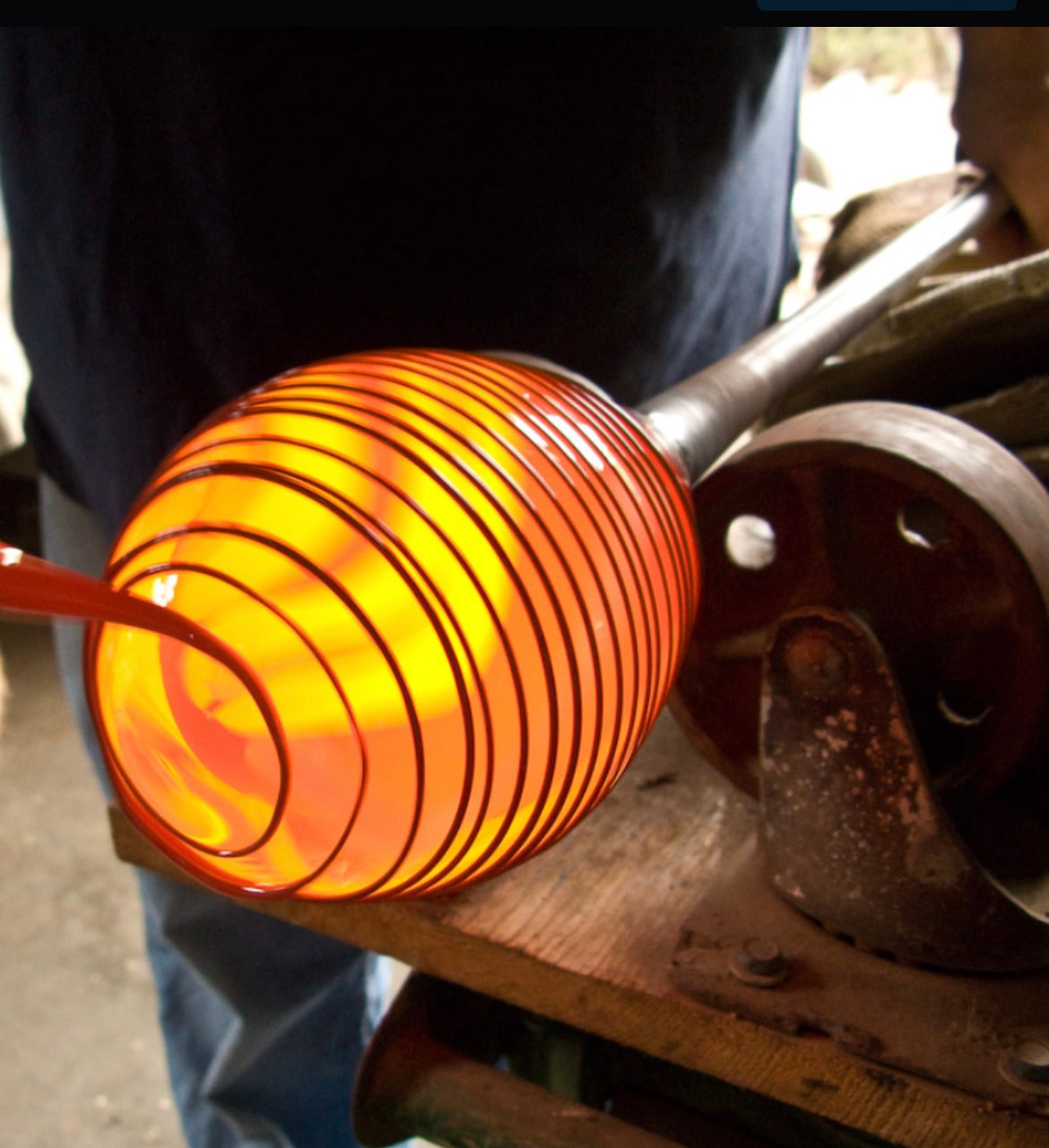 Glowing amber glass bubble on the blowpipe