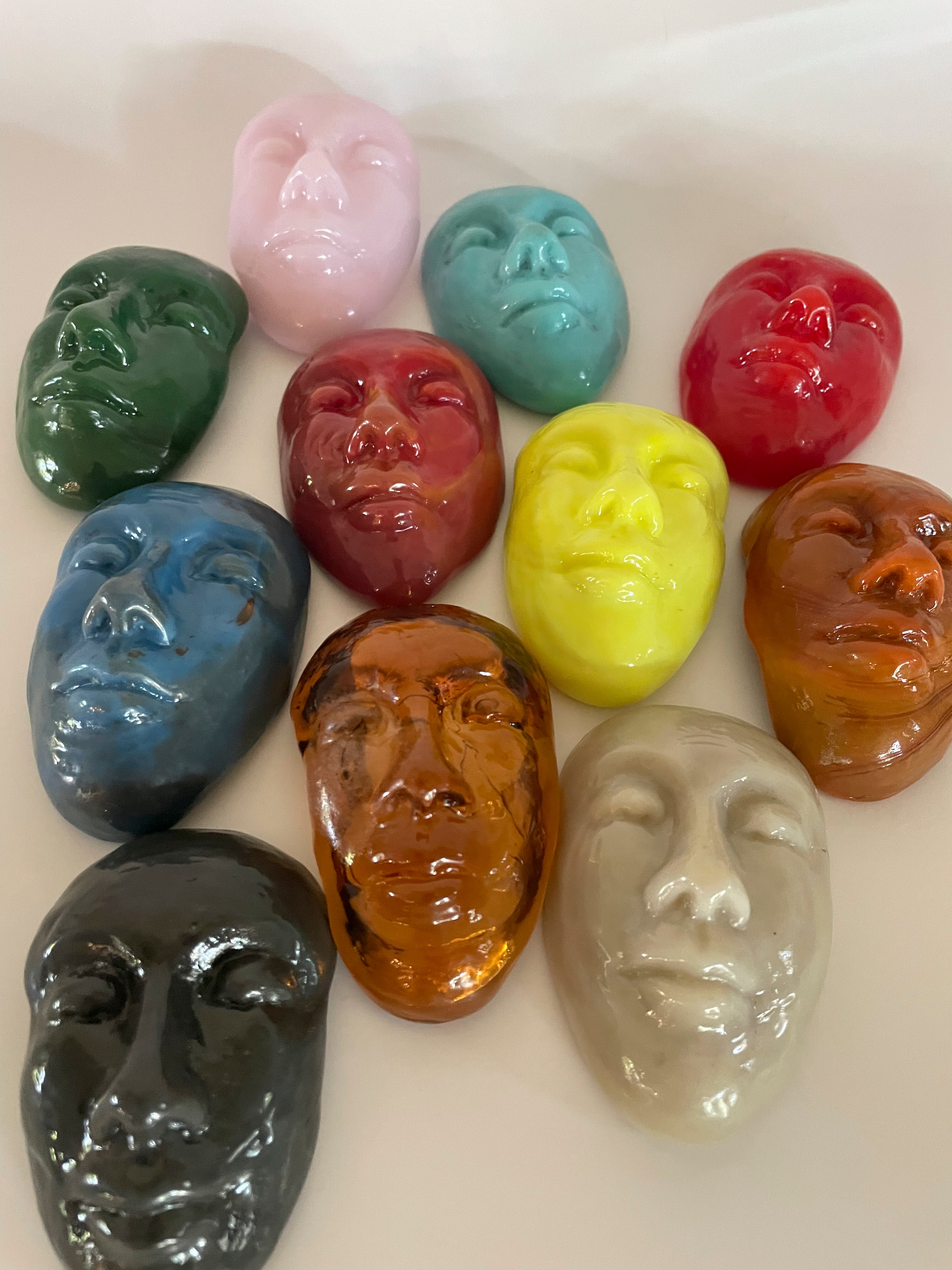 Collection of colorful blown glass face sculptures in multiple colors